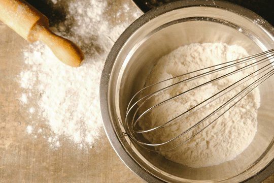 ボウルに入れられた小麦粉と製菓道具